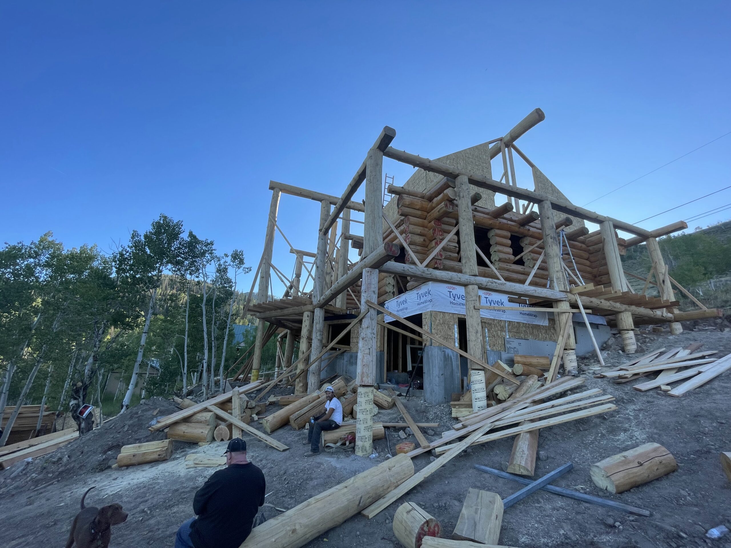Handcrafted log home under construction on a steep mountain property by Caribou Log Homes