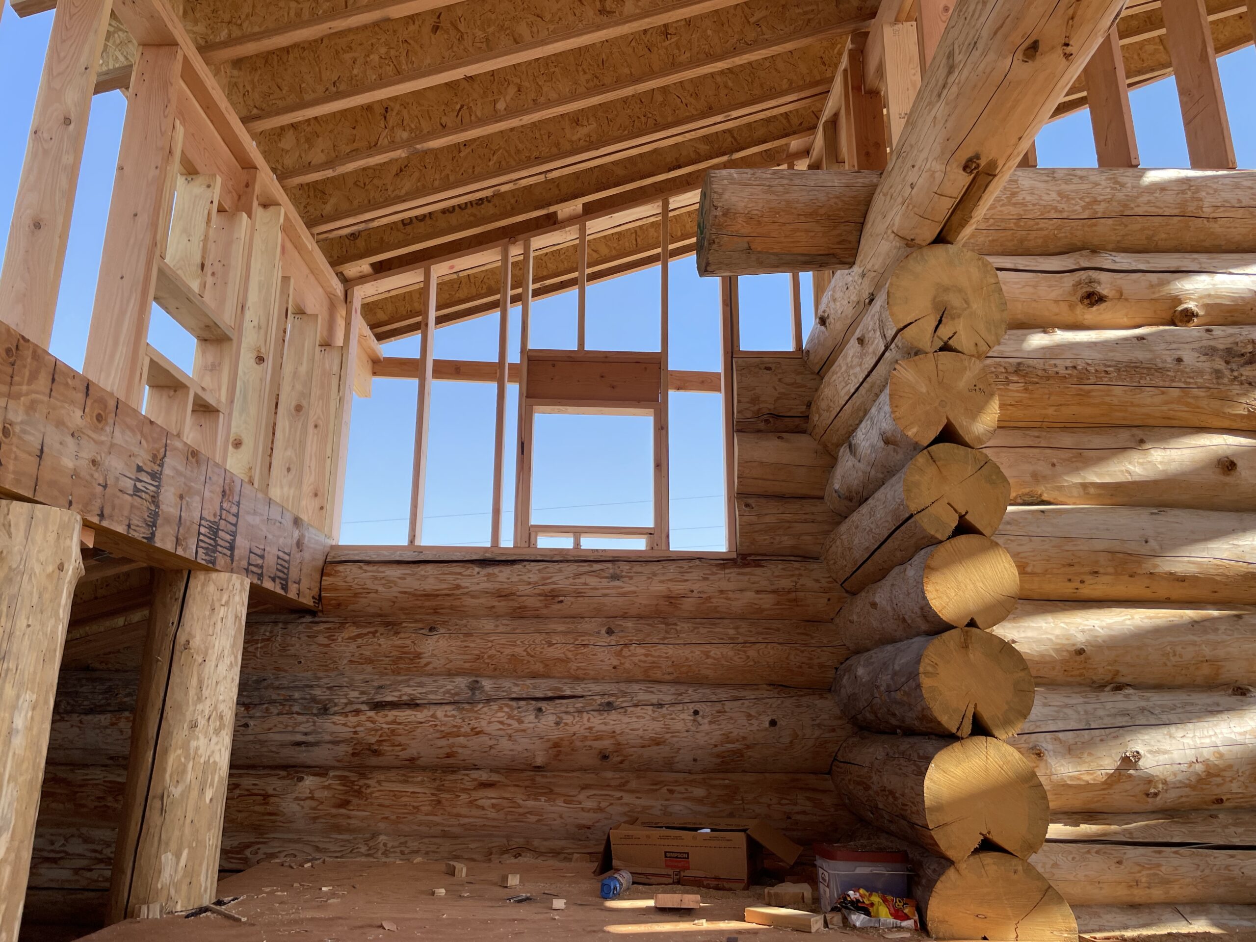 Upper wall framing above handcrafted log walls on the Burton home